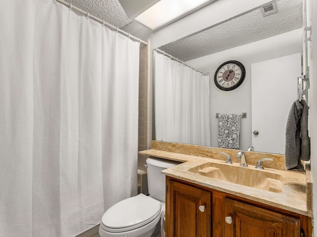 bathroom with vanity, a skylight, toilet, and a textured ceiling