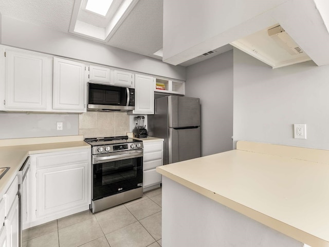 kitchen featuring white cabinetry, stainless steel appliances, light tile patterned floors, and tasteful backsplash