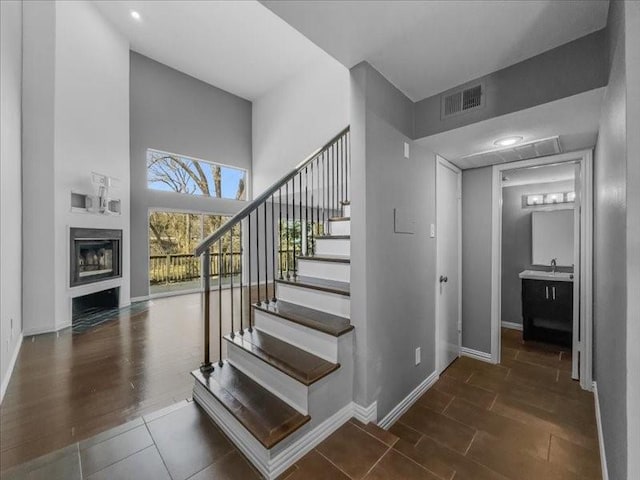 stairway featuring sink, wood-type flooring, and a high ceiling