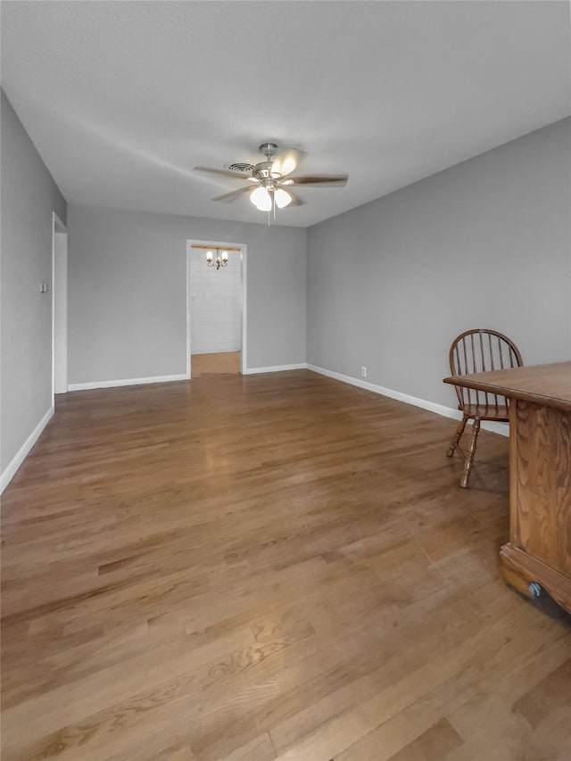 spare room featuring ceiling fan with notable chandelier and light hardwood / wood-style floors