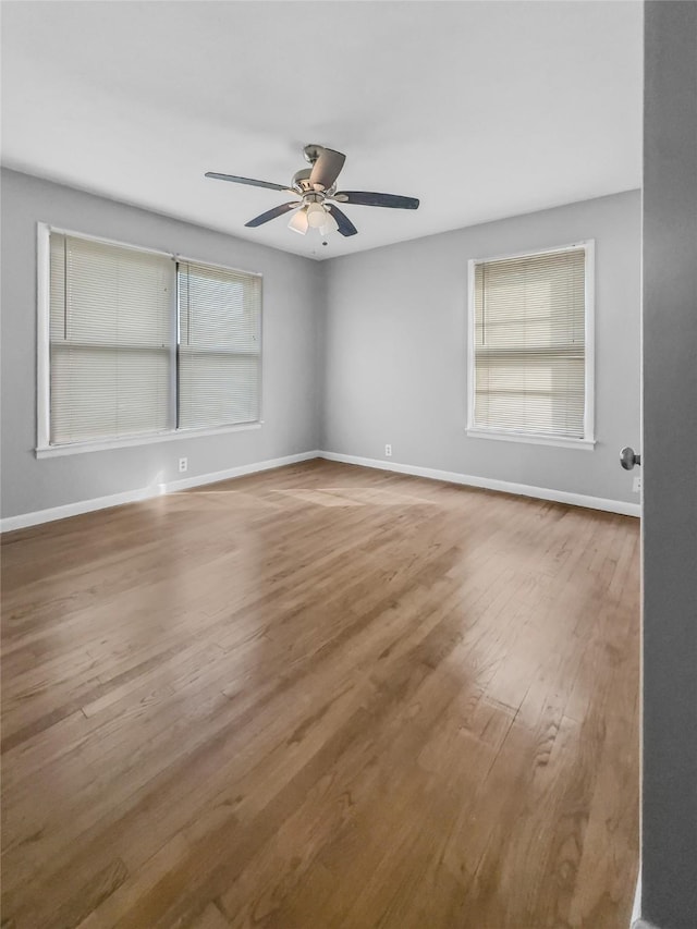 empty room with hardwood / wood-style floors, a wealth of natural light, and ceiling fan