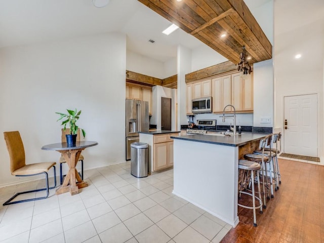 kitchen with high vaulted ceiling, appliances with stainless steel finishes, kitchen peninsula, and sink