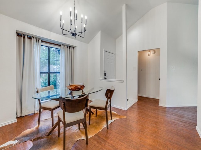 dining area with an inviting chandelier, wood-type flooring, and high vaulted ceiling