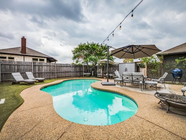 view of pool featuring a patio, area for grilling, and a fire pit