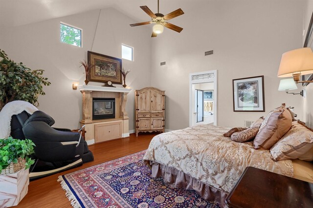 206 Pueblo Dr E, Lake Kiowa, TX 76240 - bedroom with visible vents, a glass covered fireplace, wood finished floors, and high vaulted ceiling