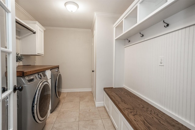 clothes washing area featuring cabinets, independent washer and dryer, ornamental molding, and light tile patterned floors