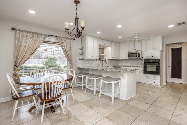 kitchen with pendant lighting, white cabinetry, oven, light stone counters, and kitchen peninsula