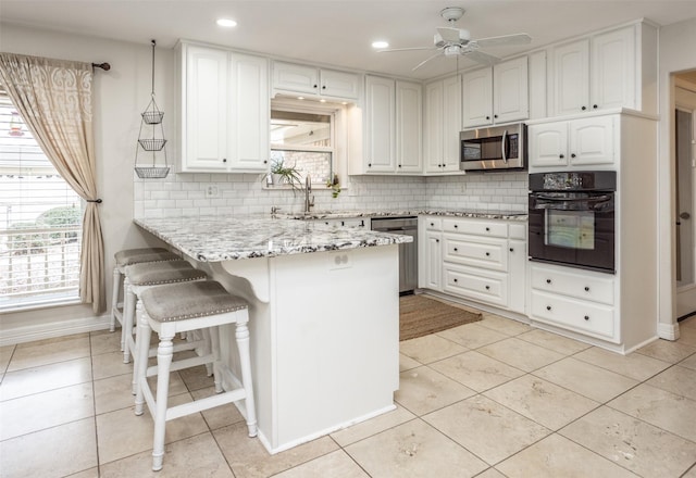 kitchen with appliances with stainless steel finishes, sink, white cabinets, a kitchen breakfast bar, and kitchen peninsula