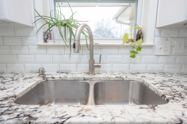 room details with white cabinetry, sink, and backsplash