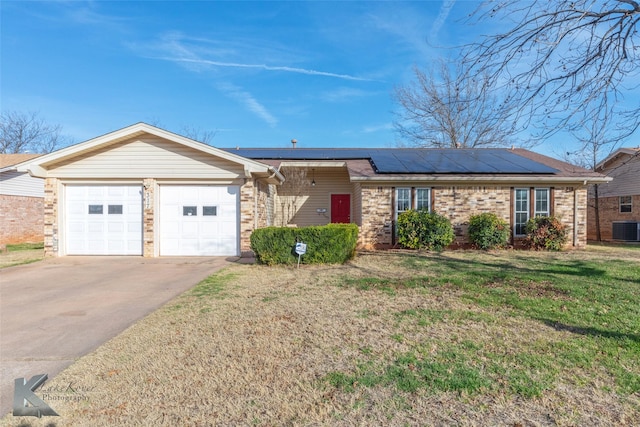 ranch-style home featuring a garage, cooling unit, a front lawn, and solar panels