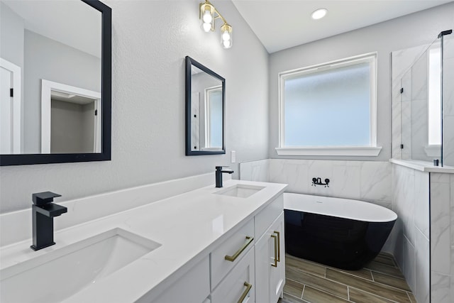 11298 Cedar Dr, Mabank, TX 75156 - bathroom featuring a tile shower, a freestanding bath, tile walls, wood tiled floors, and double vanity