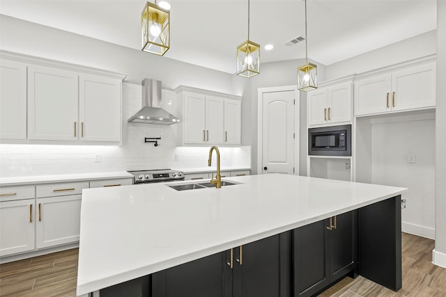 kitchen featuring wall chimney range hood, sink, and a spacious island