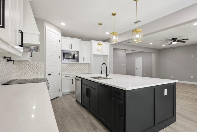 kitchen featuring appliances with stainless steel finishes, pendant lighting, white cabinetry, sink, and a center island with sink