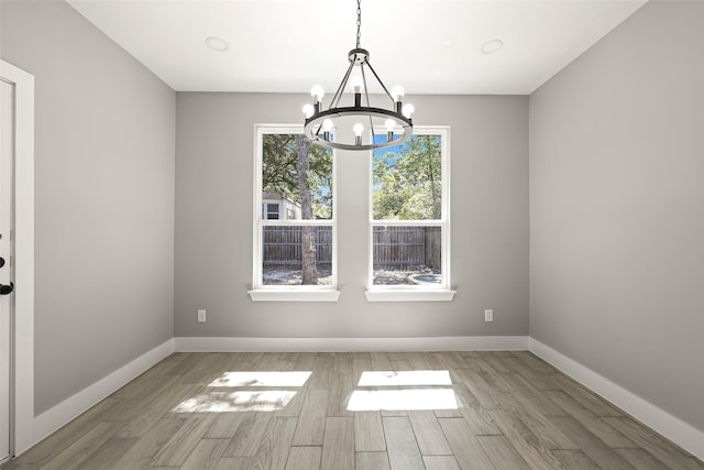 unfurnished dining area with an inviting chandelier and light wood-type flooring