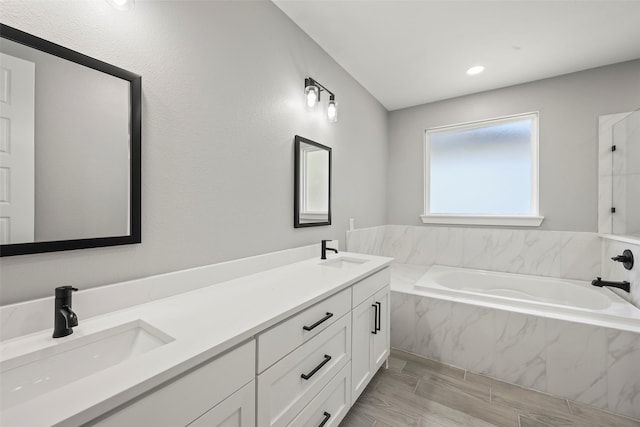 bathroom featuring vanity and a relaxing tiled tub