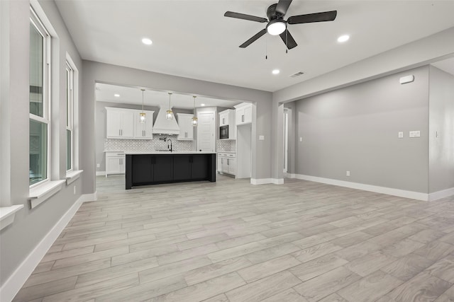 unfurnished living room featuring ceiling fan, sink, and light hardwood / wood-style floors