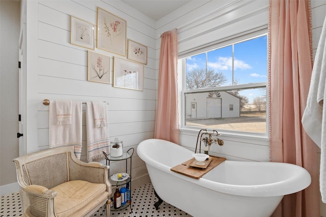 full bathroom with a freestanding tub and wooden walls