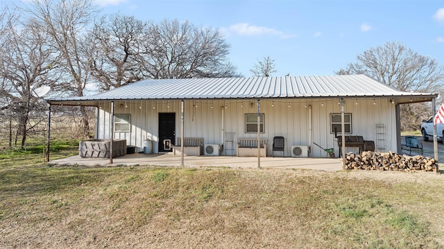 rear view of property with metal roof, a patio area, and a yard