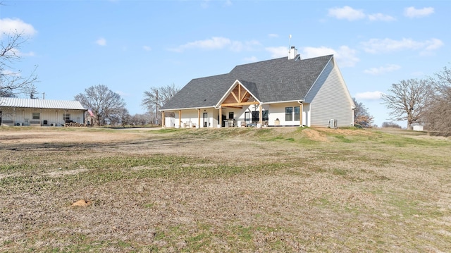 view of front facade featuring covered porch, a chimney, and a front yard