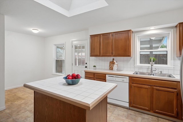 kitchen featuring decorative backsplash, tile countertops, a kitchen island, white dishwasher, and a sink