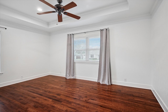 unfurnished room featuring dark wood-style flooring, a raised ceiling, and crown molding