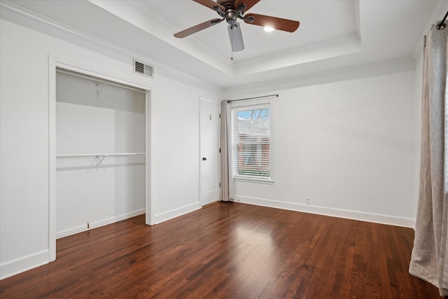 unfurnished bedroom featuring dark wood-type flooring, a raised ceiling, visible vents, and baseboards