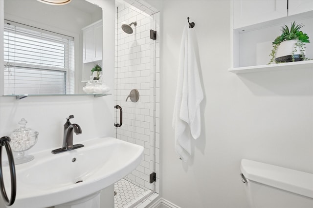 bathroom featuring a sink, toilet, and a shower stall