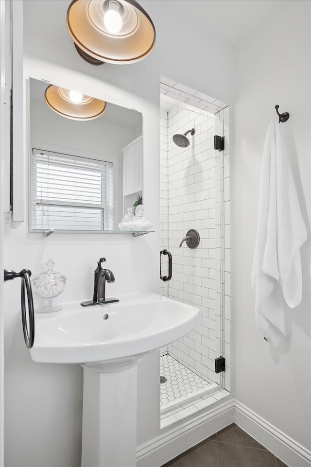 bathroom with baseboards, a sink, a shower stall, and tile patterned floors