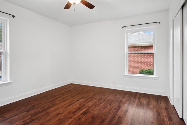 unfurnished room featuring dark wood-style floors, plenty of natural light, a ceiling fan, and baseboards