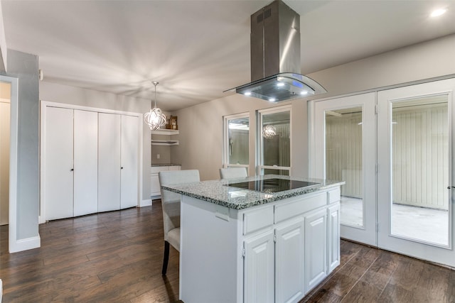 kitchen featuring a kitchen island, pendant lighting, island range hood, white cabinets, and black electric cooktop