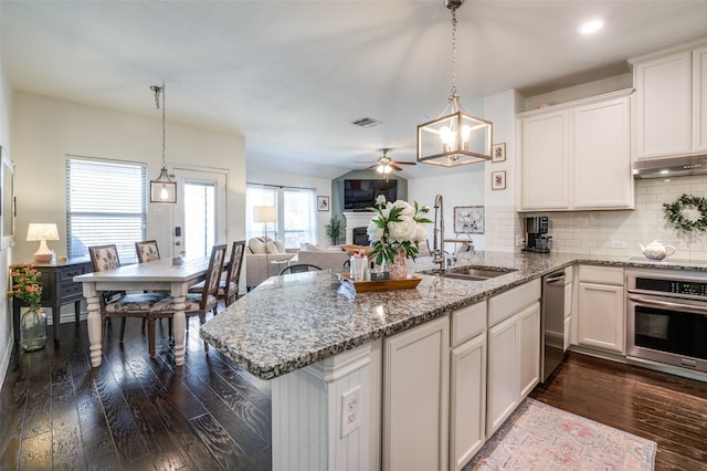 kitchen featuring pendant lighting, oven, open floor plan, and white cabinets