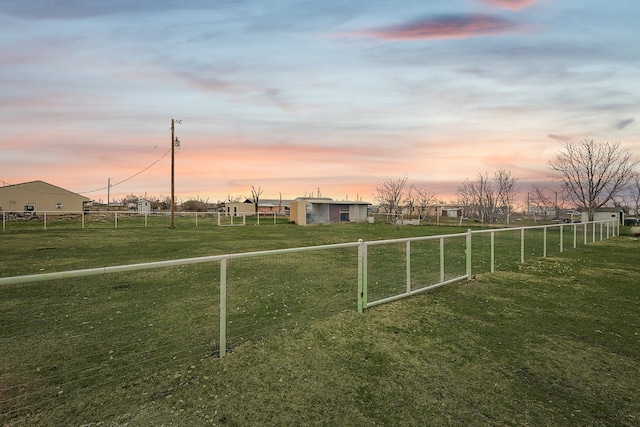 yard at dusk featuring a rural view