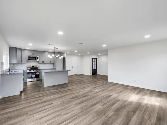 kitchen featuring sink, appliances with stainless steel finishes, gray cabinetry, a center island, and decorative light fixtures