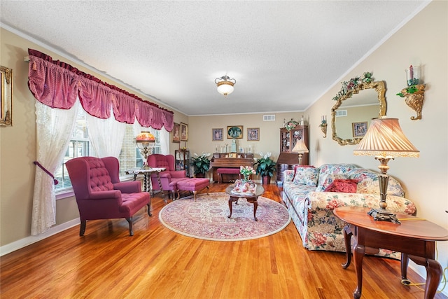 living area featuring a textured ceiling, wood finished floors, visible vents, and crown molding