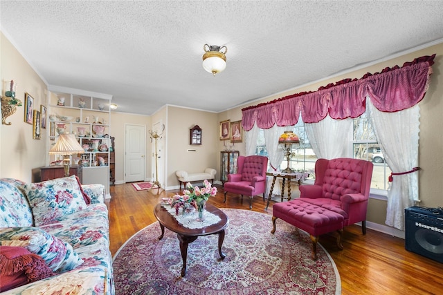 living area with a textured ceiling, baseboards, and wood finished floors