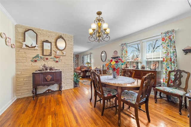 dining area with ornamental molding, a notable chandelier, and wood finished floors