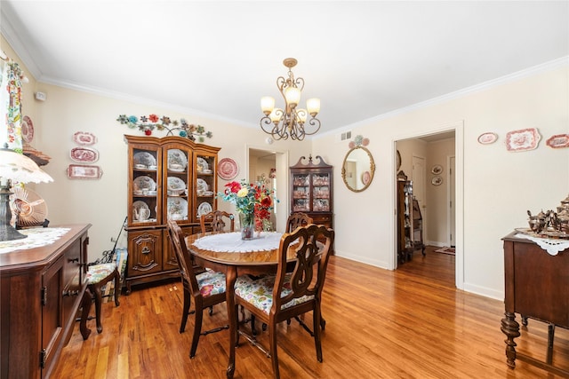 dining room with light wood-type flooring, baseboards, a chandelier, and crown molding