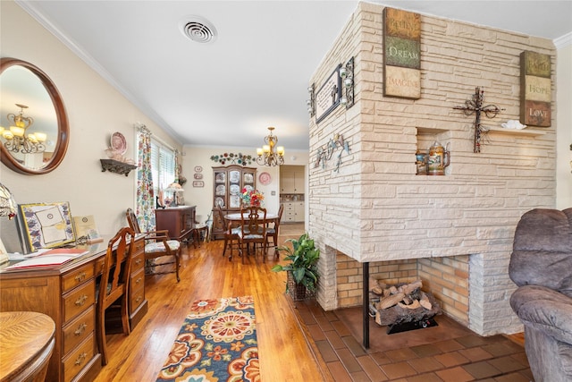 hall featuring crown molding, wood finished floors, visible vents, and an inviting chandelier