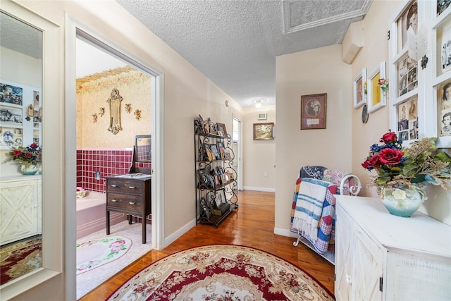 hall featuring baseboards, a textured ceiling, and wood finished floors