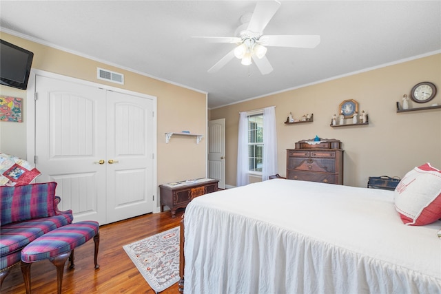 bedroom featuring visible vents, a ceiling fan, ornamental molding, wood finished floors, and a closet