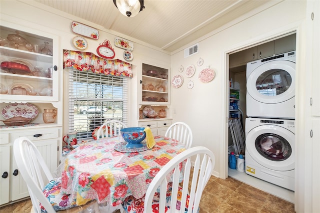 clothes washing area with stacked washer and dryer, laundry area, and visible vents