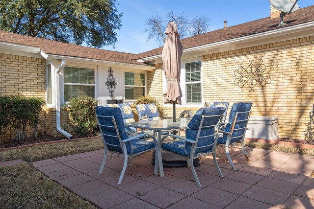 rear view of house featuring a patio, brick siding, a chimney, and a lawn