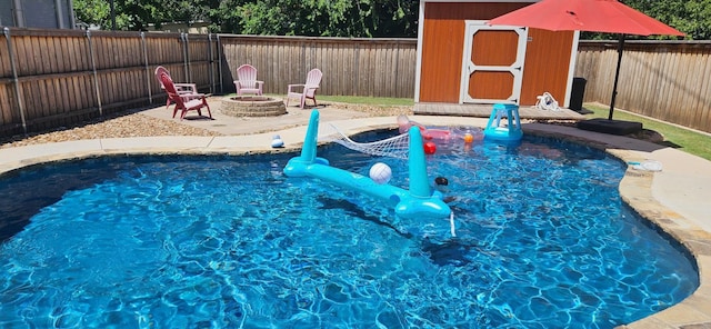 view of swimming pool with a storage shed, an outdoor fire pit, a fenced backyard, an outbuilding, and a patio area