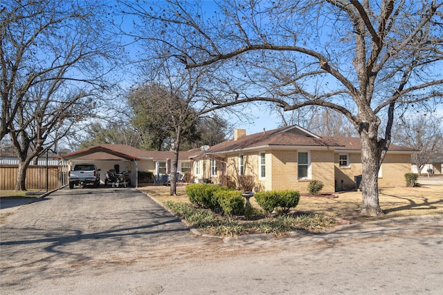 ranch-style home with a chimney, fence, aphalt driveway, and brick siding