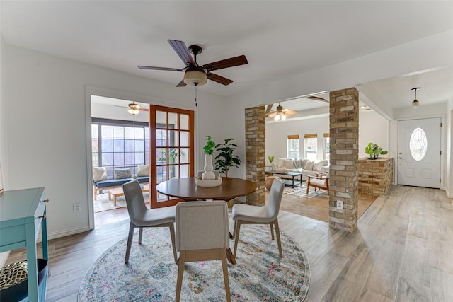 dining area with ornate columns and light hardwood / wood-style flooring