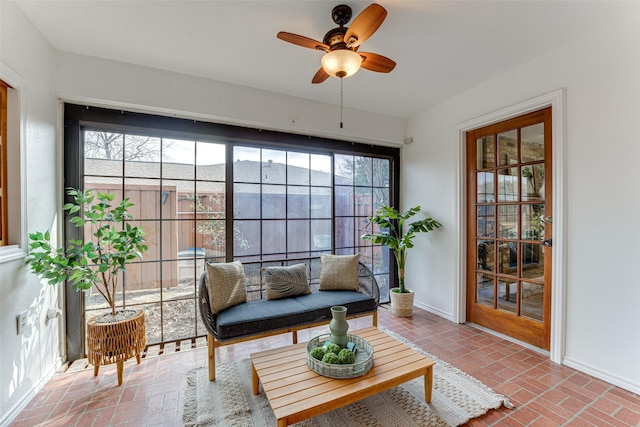 living room with a brick fireplace, beam ceiling, a raised ceiling, and ceiling fan