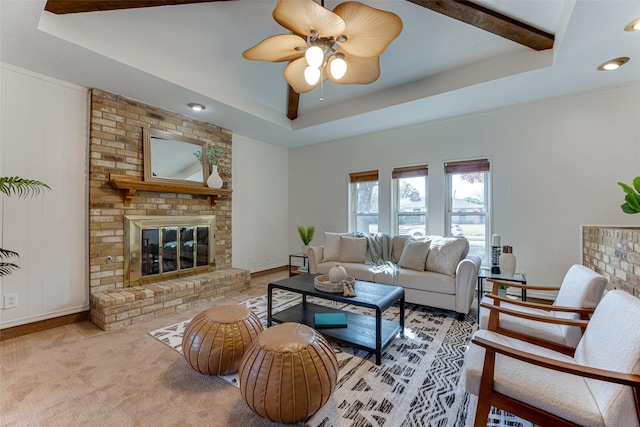 living room featuring beam ceiling, a tray ceiling, a fireplace, and ceiling fan