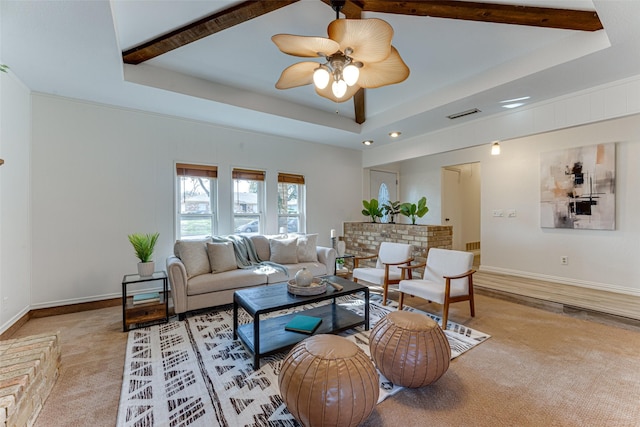 carpeted living room with a raised ceiling, ceiling fan, and beamed ceiling