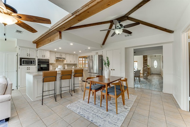 tiled dining room with ceiling fan and vaulted ceiling with beams