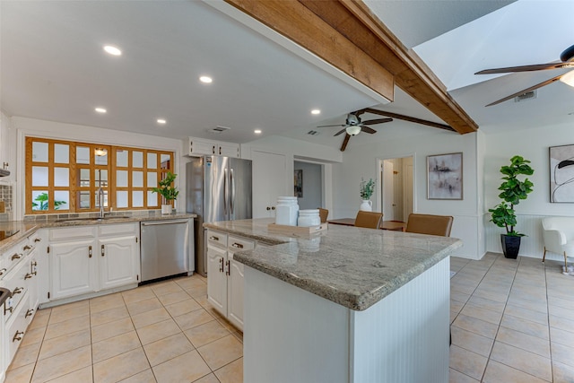 kitchen featuring appliances with stainless steel finishes, white cabinetry, sink, a center island, and light stone countertops